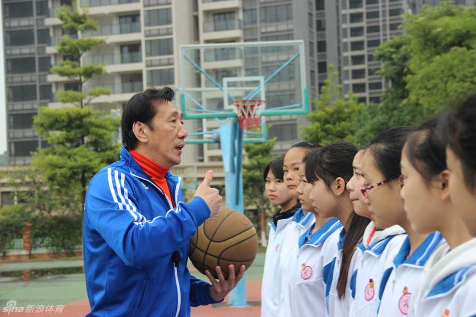 前深圳主帅李群的篮球人生下半场:投身校园公益,从华师附小抓起 李群弯腰俯身纠正小队员的运球姿势,眼神专注,手把手教学