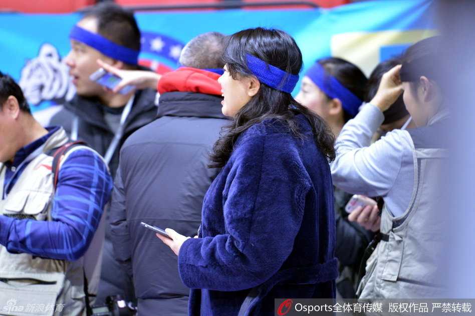 一名戴着发带的记者正低头专注地用手机发着信息，似乎正在向后方的编辑部传递着赛场内这一独特的风景线，将无声的抗议通过电波传向远方。