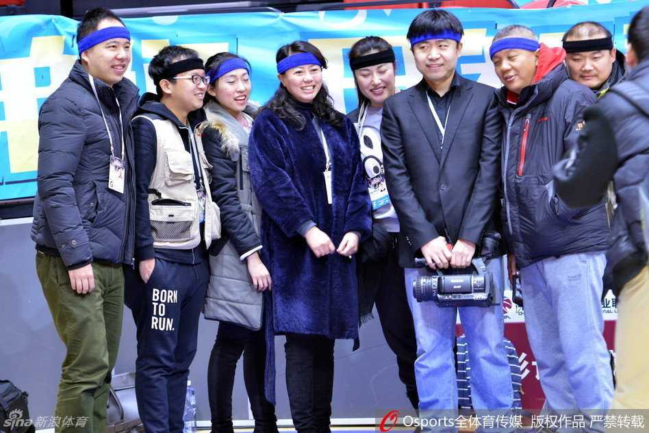 乌鲁木齐红山体育馆内，几位佩戴着蓝色发带的媒体老师正全神贯注地调试着手中的长枪短炮，额间的发带在紧张的赛场氛围中显得格外醒目，仿佛一种无声的誓言。