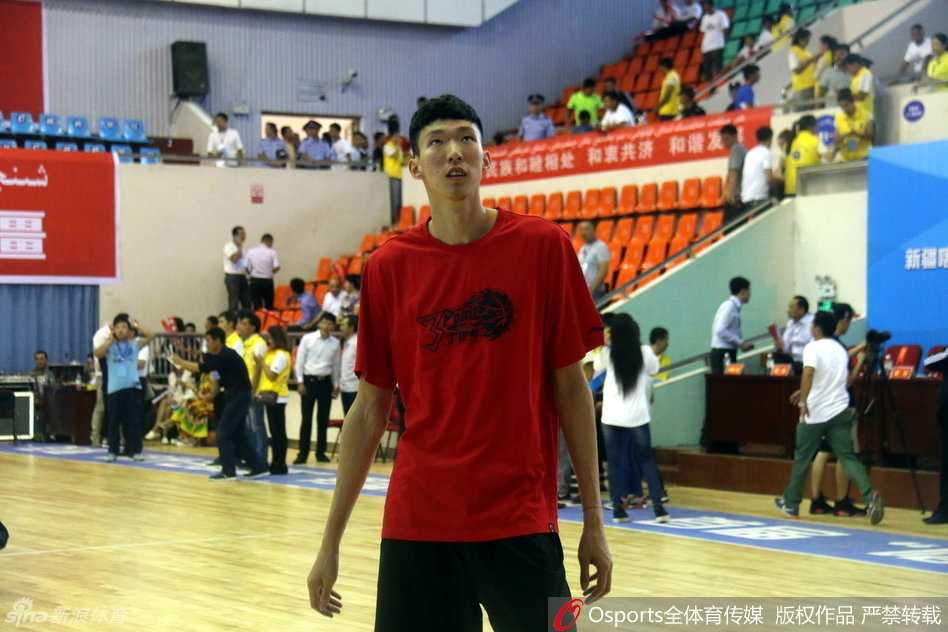 热情的喀什球迷在赛后找到新疆队球员李根合影，李根面带微笑配合球迷，这一幕展现了篮球运动在当地的深厚群众基础。