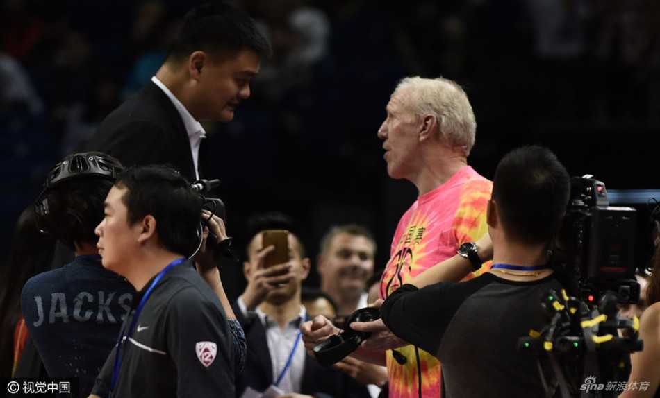 姚明与前中国男篮名宿马健在看台上热切交谈，两人目光如炬，仿佛在共同回顾往昔峥嵘岁月。