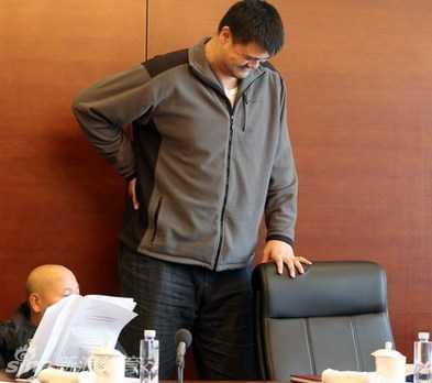 姚明在众人注视下缓缓从大号座椅上站起，高大的身影在严肃的会场中格外醒目，他正走向那把等待着他的普通椅子。