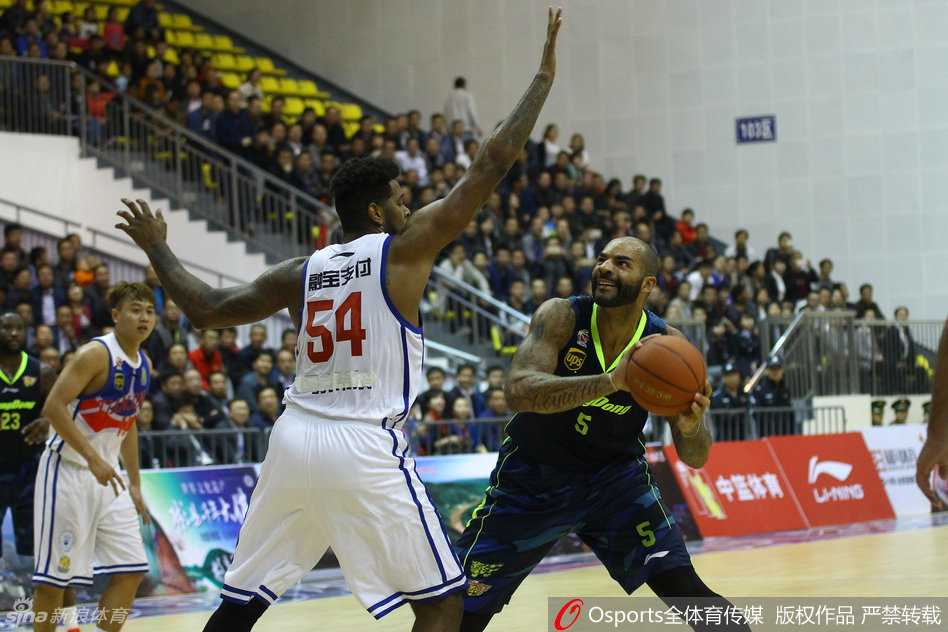 季前赛彬县站群雄逐鹿,广东天津上演巅峰对决 前NBA名将布泽尔身穿广东队服,面对天津泰勒的贴身长臂干扰,高高跃起准备施展他招牌式的直臂跳投,眼神专注而坚定。