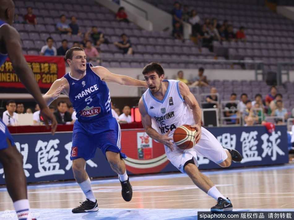 斯坦科维奇杯北京揭幕 法兰西男篮内线强攻击退阿根廷 阿根廷队员在夹缝中寻找机会,他利用一个急停变向完成突破上篮,尽管身体失去平衡,依然奋力将球抛向篮筐。