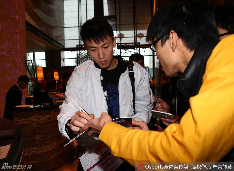 旧地重游显锋芒 携美同行暖心房 刘晓宇被几位热情球迷簇拥,他微微侧身低头,手中的笔在球衣上划过,嘴角勾起一抹宠溺的弧度,现场气氛温馨而热烈。