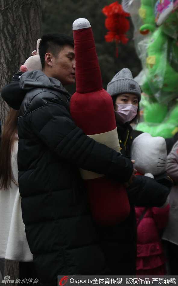 春节邂逅温情:篮球国手常林地坛庙会秀最萌身高差 常林与女伴在一个售卖传统工艺品的地坛庙会摊位前选购,他微微低头倾听女伴的话语,205厘米的身高在人群的映衬下宛如巨人,画面充满了温馨的日常气息。