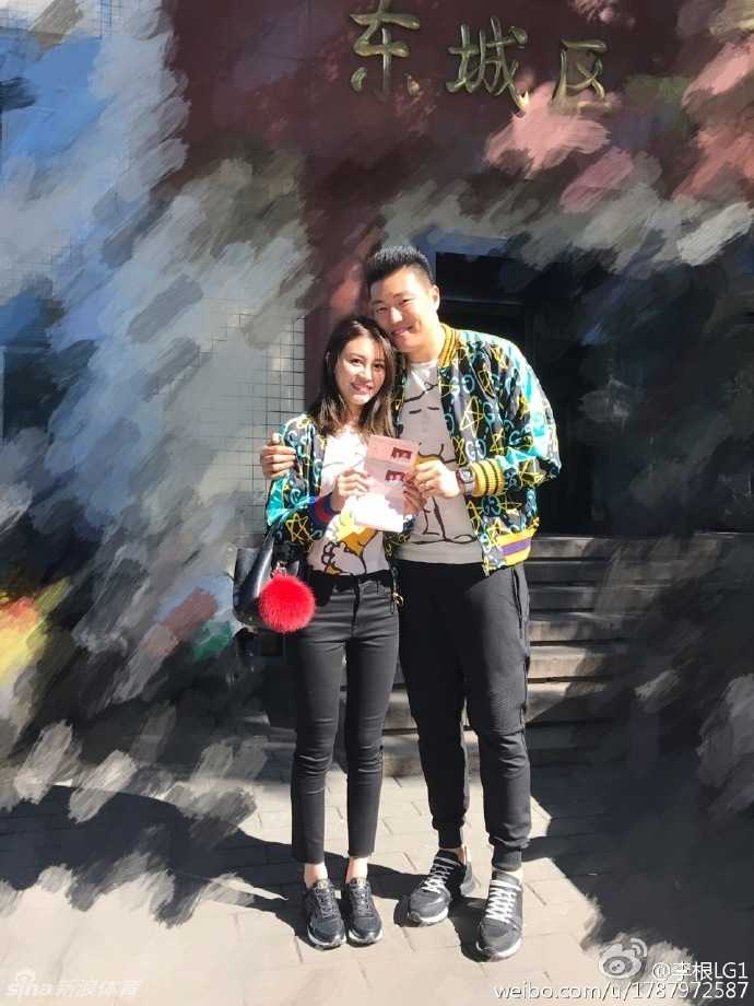 李根身着休闲运动装，轻松地将满脸幸福笑容的妻子高高扛起，妻子在空中挥舞着双手，两人的互动充满了童趣与甜蜜。