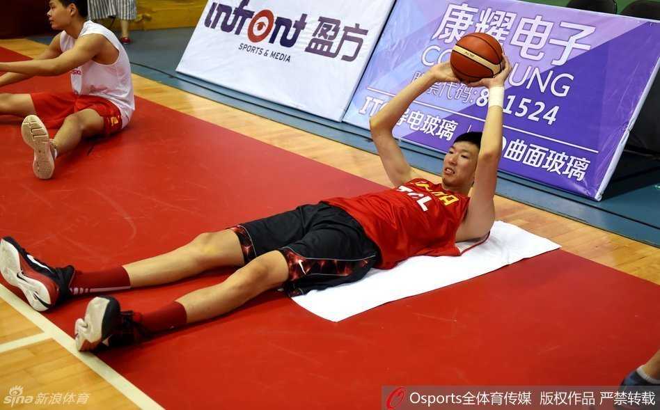 汗水与欢笑:男篮集训备战纪实 可兰白克侧身倾听,与穿着教练服的胡雪峰认真交流战术,眼神中充满对篮球的思考;身后的李慕豪正俯身进行腿部拉伸,肌肉线条清晰可见。