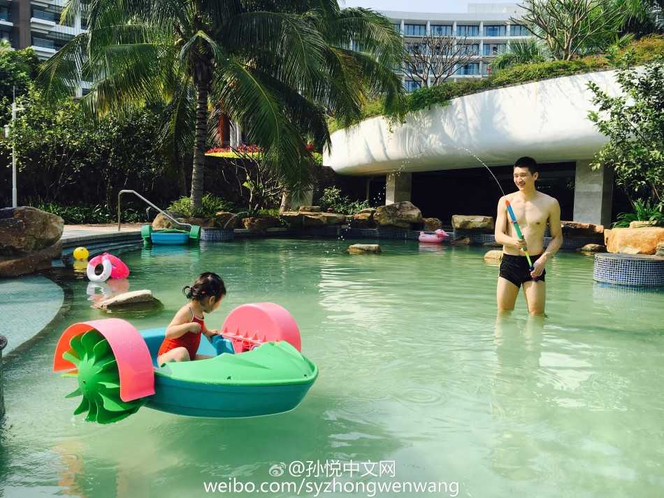 孙悦双手扶着女儿小月亮的游泳圈，父女俩在泳池中面对面对视，露出灿烂幸福笑容