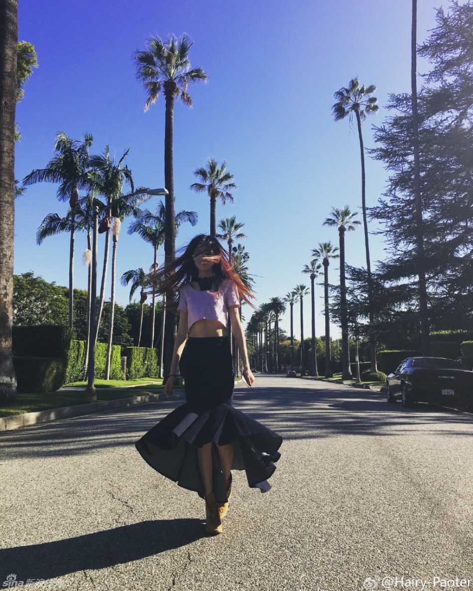 王仕鹏与爱妻李跑的幸福旅途:镜头下的长腿女神与温情漫画 李跑身着休闲装扮,在异国建筑的背景下回眸一笑,一双美腿在阳光下显得格外修长,画面充满时尚街拍的随意感。