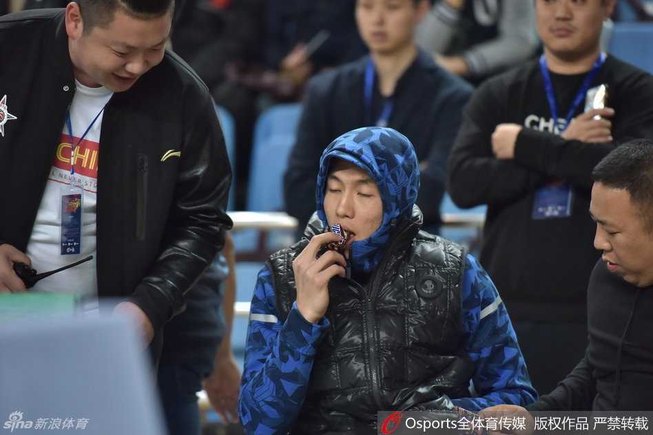 秋日暖阳下的球场童趣:郭艾伦热身赛“全副武装”吃糖记 郭艾伦站起身在场边活动,厚实的外套显得他有些笨拙可爱,他依然不忘拿着那根棒棒糖,仿佛这是他在这个寒冷秋日里最重要的伙伴,脸上写满了“心情不错”。