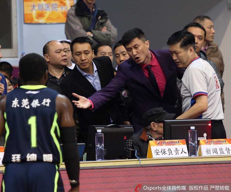 东莞队球员张凯飞身扑向底线救球，他的身体几乎与地板平行，双手奋力将球拨回场内，脚尖在底线的白线上划出一道模糊的痕迹，裁判的视线紧紧跟随。