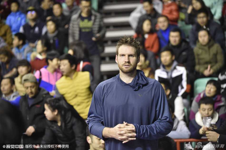 辽宁队老将杨鸣和兰多夫在台下就座，他们手里似乎拿着带有纪念意义的篮球或签名物品，神情专注地看着台上的发言。