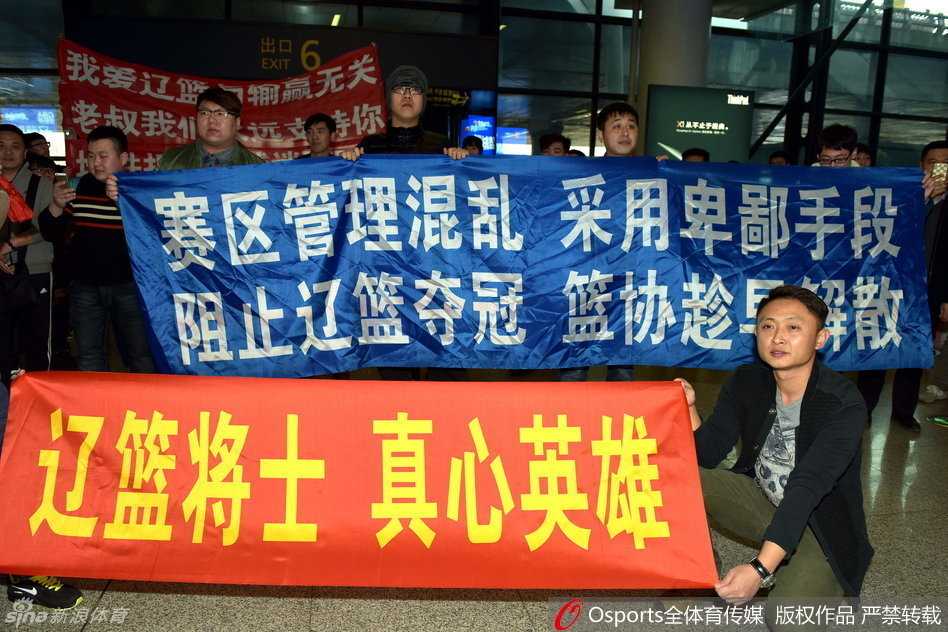 辽沈球迷含冤接机,标语声声讨伐篮协不作为 人山人海的接机大厅里,一名辽宁男篮球迷眼含热泪,高高举起写着“还我公平”的白色纸牌,眼神中充满委屈与坚定。