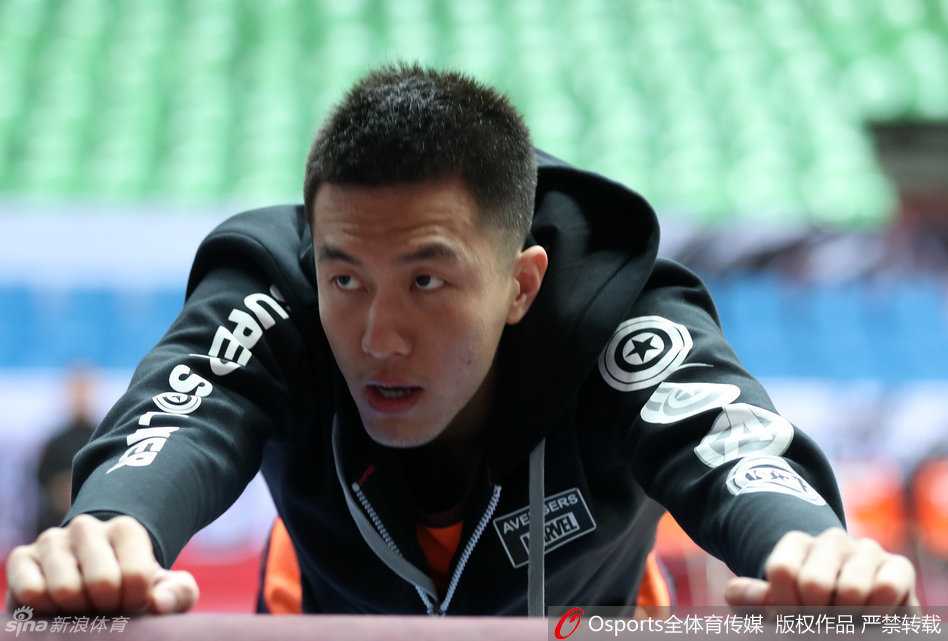 场边的郭艾伦表情格外轻松，他一边进行着拉伸训练，一边露出标志性的自信微笑，仿佛对即将到来的比赛胸有成竹。