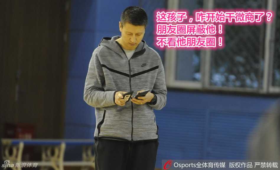 主帅郭士强手持手机却心系训练场，目光越过屏幕投向远处的弟子，面容沉静，眼神中透露出对球队备战情况的运筹帷幄。