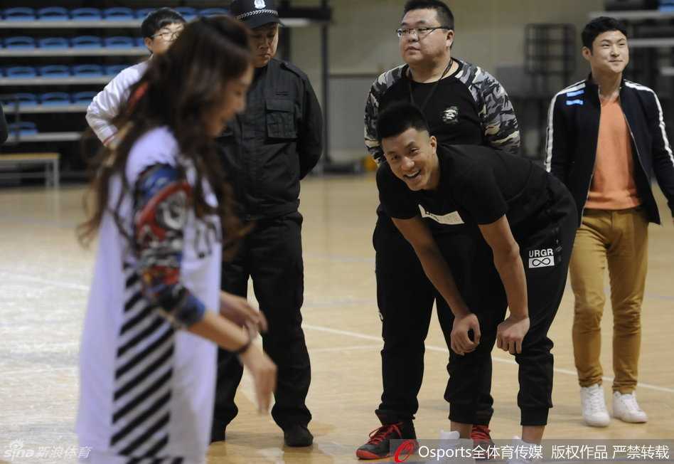 郭艾伦伸了个大大的懒腰，脸上带着一丝倦意却依然挂着微笑，旁边的女粉丝们见状发出善意的笑声，眼神里满是关切与喜爱。