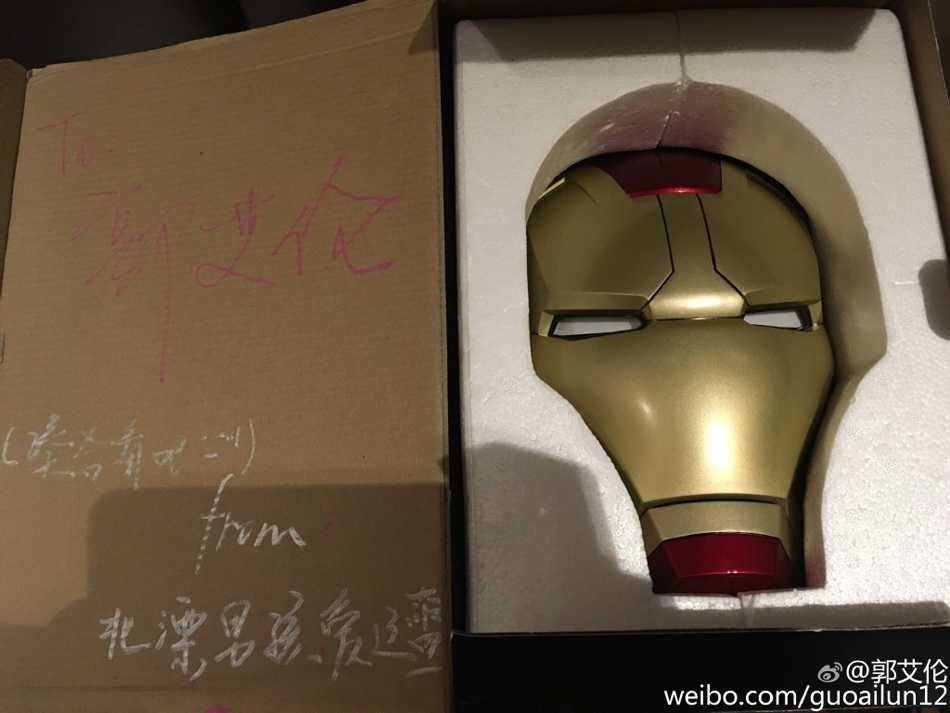 郭艾伦单手举起沉甸甸的钢铁侠头盔，眼神中充满好奇与惊喜，嘴角不自觉地上扬，像个得到了梦寐以求玩具的大男孩。