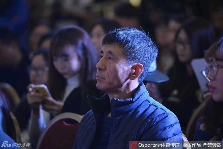 郭艾伦双手捧着定制人偶手机套，凑近眼前细细打量，眼神里充满好奇与喜爱，嘴角的笑意透出满意。