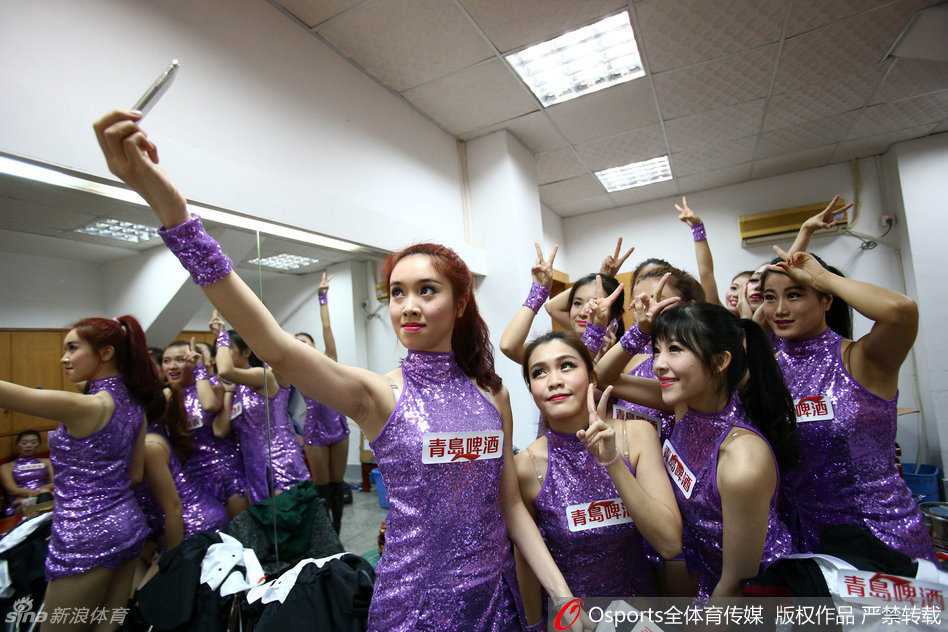 镜头定格在一位‘劈叉美女’的高光时刻，她在一字马动作中展现出惊人的柔韧度，双手轻轻触地，微卷的长发垂落，仿佛一只在球场中央优雅休憩的黑天鹅。