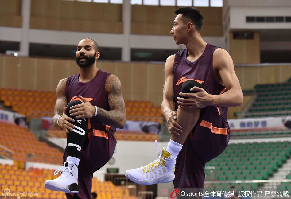 阿联在训练间隙低头整理鞋带，他脚上的球鞋品牌标识清晰可见，与身旁队友的联赛赞助商鞋款形成鲜明对比