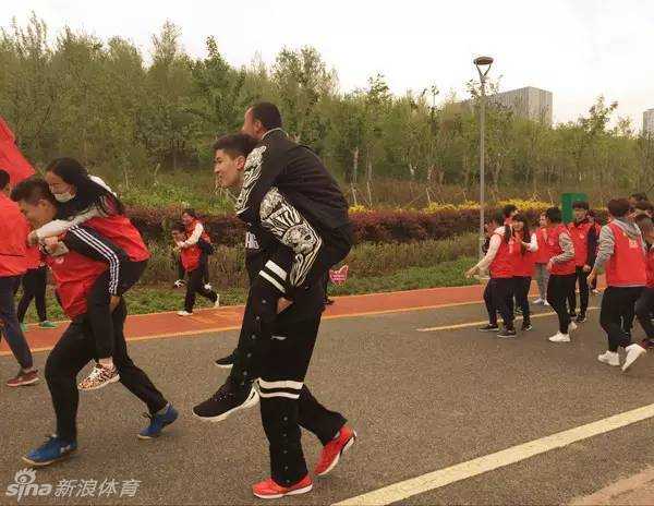 风雨同行,为爱酷跑:西热力江与阿不都的公益征途 西热力江背着队友阿不都沙拉木奋力前行,两人脸上洋溢着笑容,在公益跑的游戏中默契配合,展现了深厚的兄弟情谊。