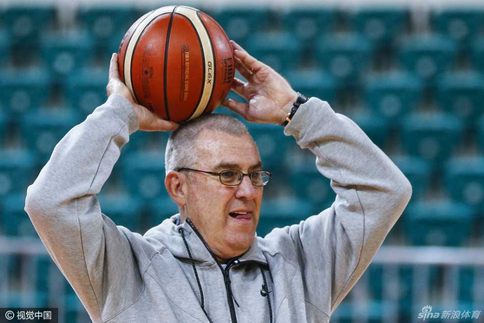 马赫双手持球置于胸前，身体微微弯曲做出对抗姿态，眼神坚定地盯着前方，亲身向队员演示如何在高压防守下稳稳护住球权。