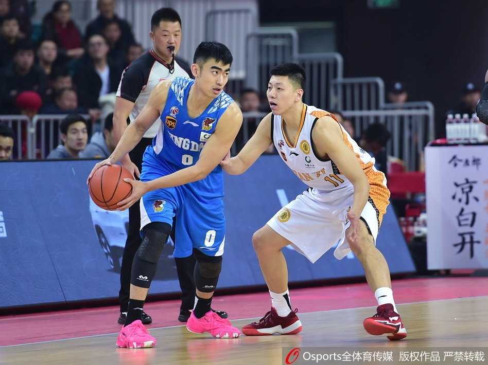 山西队核心曾令旭运球过半场，他冷静地观察着场上局势，举手示意队友跑位，青岛队的防守球员寸步不离紧紧跟随。