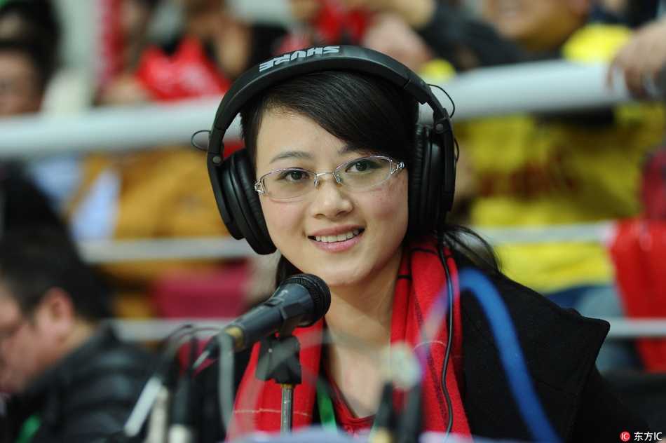 美女解说员在聚光灯下全神贯注，眼神紧追场上球赛，耳麦下是一张精致而认真的面庞