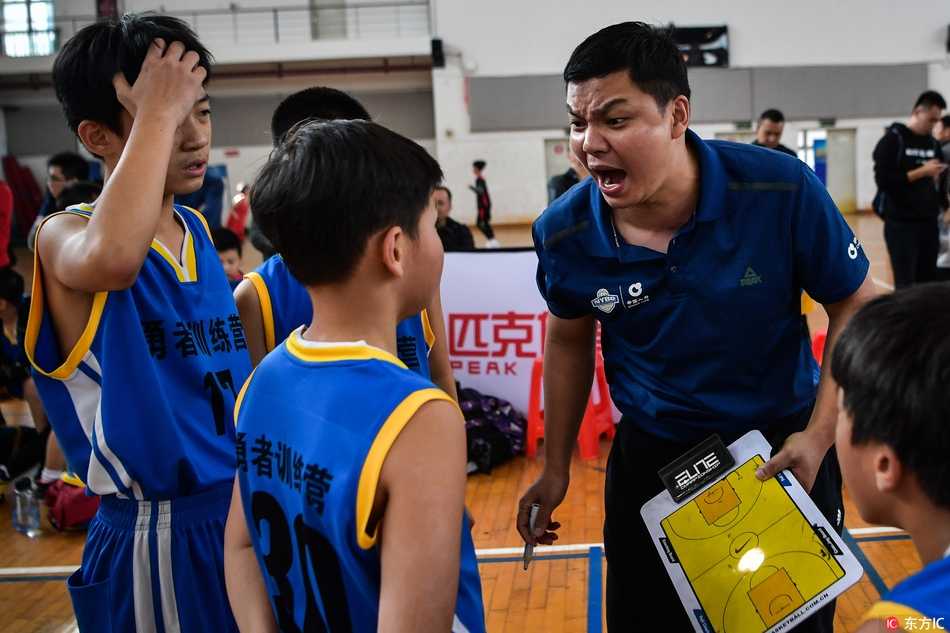 NYBO赛场运筹帷幄 U12教练激情指挥点燃篮球少年梦 比赛进入白热化阶段,教练激动地从座位上站起来,双手拢在嘴边形成喇叭状,大声指挥着场上的攻防,面部表情因投入而显得十分丰富。