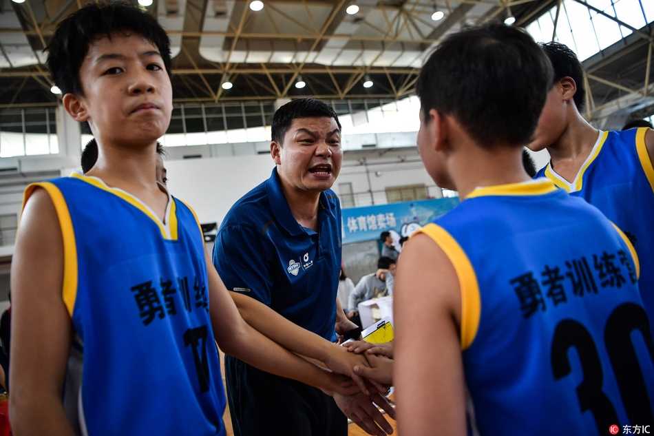 NYBO赛场运筹帷幄 U12教练激情指挥点燃篮球少年梦 暂停时间,教练快速地向围成一圈的小球员们讲解战术,他手中比划着战术路线,眼神坚定,队员们则个个凝神静听,充满信任。