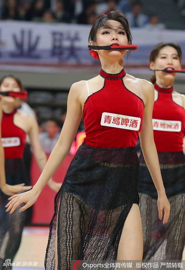 一位队员正在侧身旋转，裙摆随之飞扬成一道完美的弧线。她手中的扇子高高举起，扇面上的刺绣在灯光下熠熠生辉。背景中，观众席上无数手机闪光灯亮起，记录下这惊艳的瞬间，仿佛是在为这场传统与现代交融的表演献上最热烈的掌声。