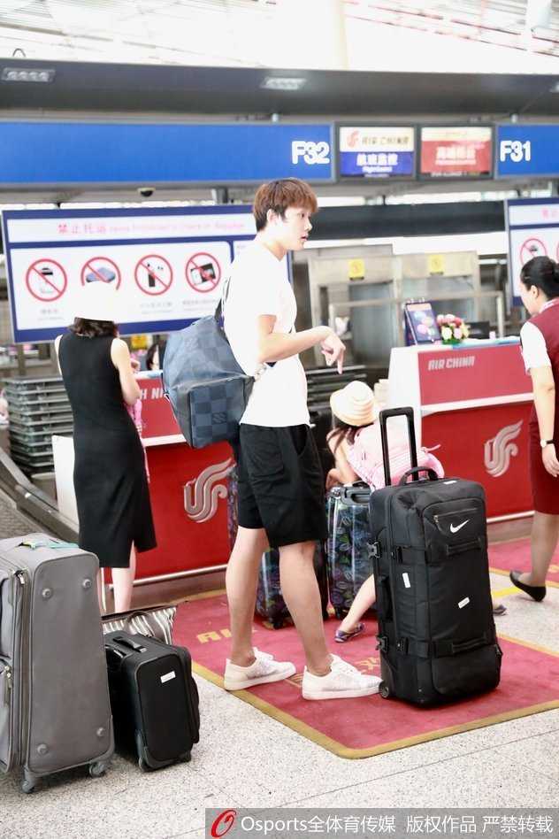 在机场出口，丁彦雨航被热情的球迷认出并索要签名，他停下脚步微微弯腰，耐心地为球迷签字，身旁的安保人员则在维持秩序。