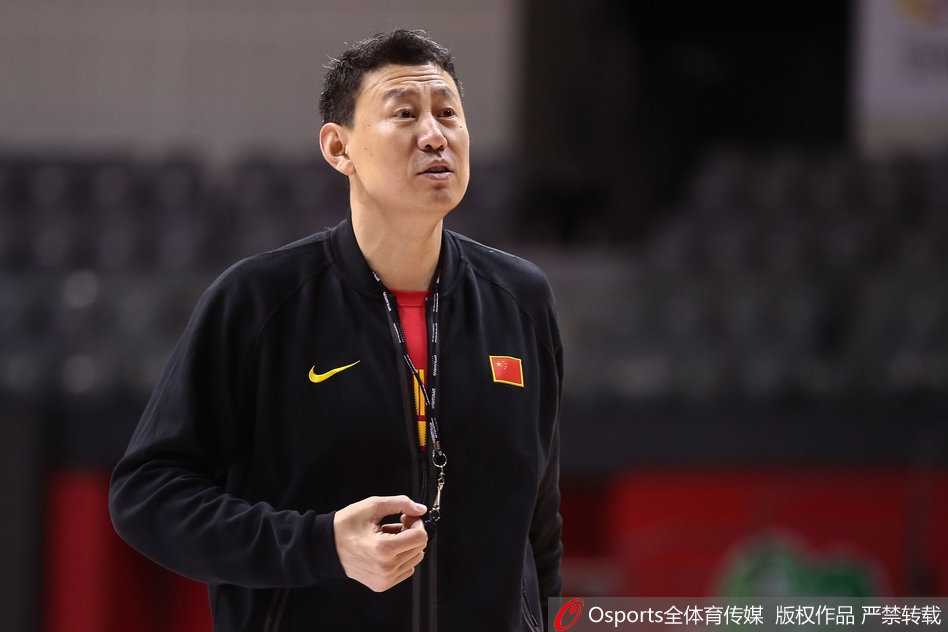 训练间隙的丁彦雨航神情专注地听着教练讲解，嘴角微微上扬，似乎对即将到来的战术布置心领神会，眼神中闪烁着机智与笃定的光芒。