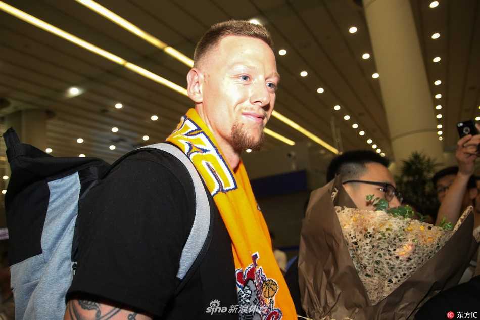 走出机场通道的明纳拉斯单手轻推着行李车，另一只手自然地护在妻子身后，细节处展现着新婚丈夫的体贴与保护欲