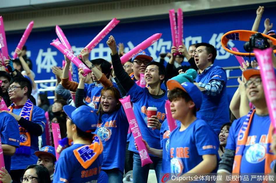 一位戴着眼镜的斯文男球迷被镜头捕捉，他手中的助威牌上画着一个可爱的漫画版丁彦雨航，旁边配文