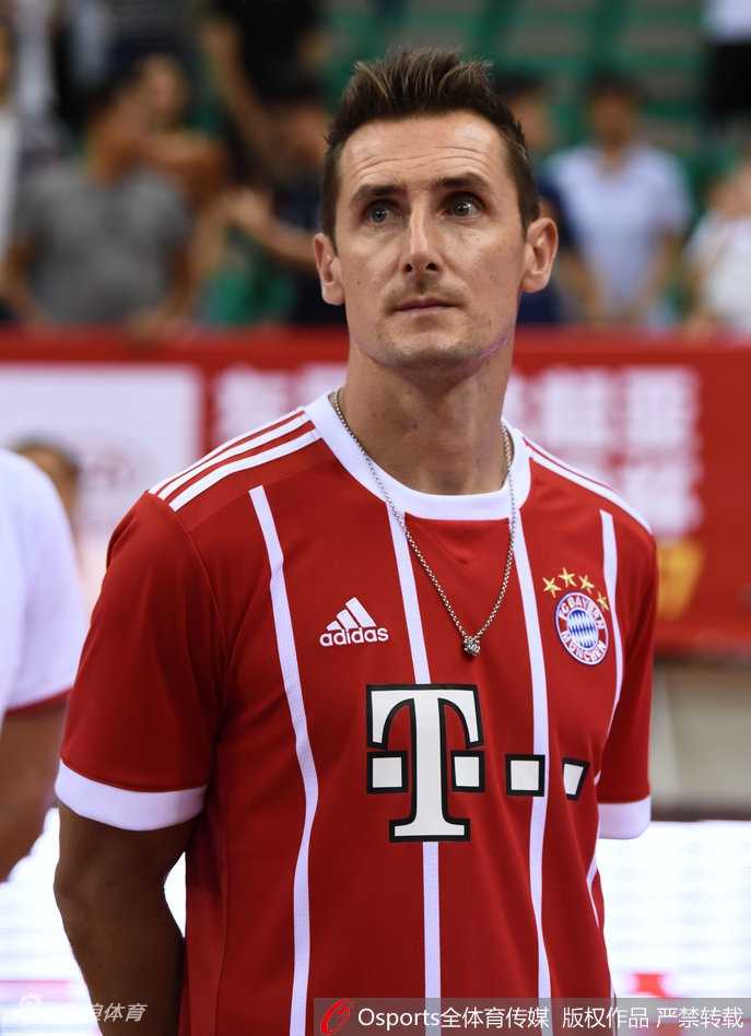 世界杯传奇“K神”跨界助阵斯坦科维奇杯 为男篮中德战开球 镜头拉近,克洛泽与现场主持人谈笑风生,他深邃的眼眸中带着好奇与亲切,倾听关于这场篮球赛的介绍,背景是色彩斑斓的斯坦科维奇杯赛场。