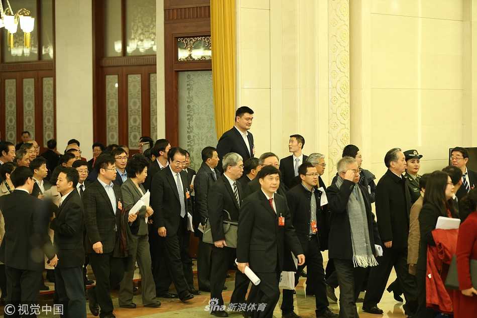 在大会堂巨大的廊柱下，姚明独自一人行走，由于身高突出，他与周围代表形成了有趣的身高差，这独特的视角仿佛隐喻着他在体育改革道路上所站的高度与肩负的独特责任。