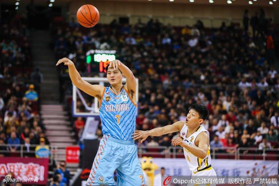 五棵松体育馆内灯火通明，北控男篮身披白色战袍与身穿深色球衣的新疆队员在跳球瞬间同时跃起，双方手臂在空中交织，仿佛一场战争正式打响。