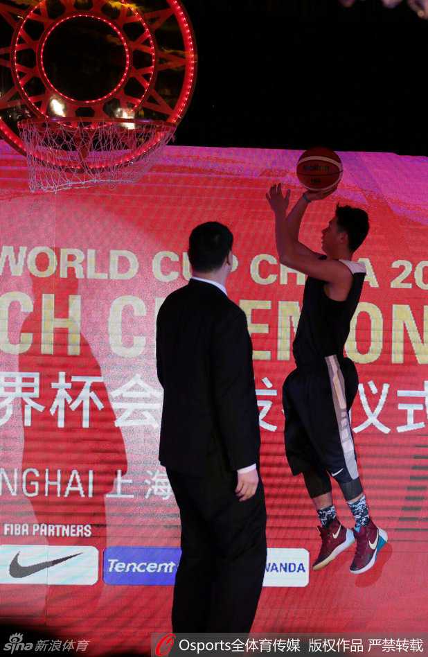 在京剧表演的映衬下，舞台上的姚明全神贯注地凝视着即将揭晓的会徽，眼中满是对未来的期许