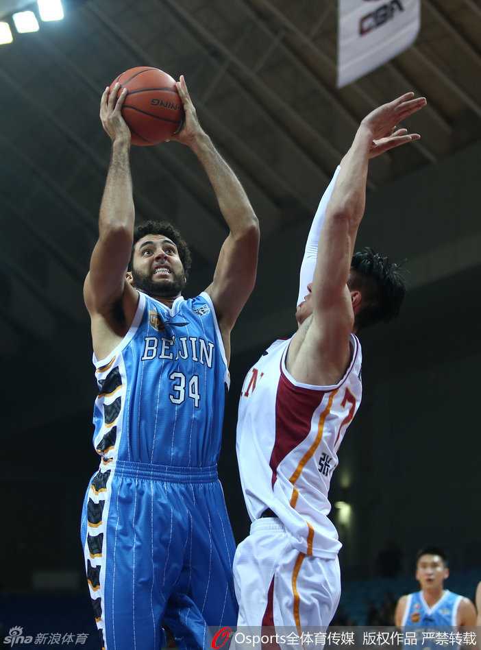 北京队外援在对方严密的内线防守中强行进攻，在与对方肌肉碰撞后失去平衡，身体倾斜着摔倒在地，眼神中依旧紧盯着那未进的篮筐。
