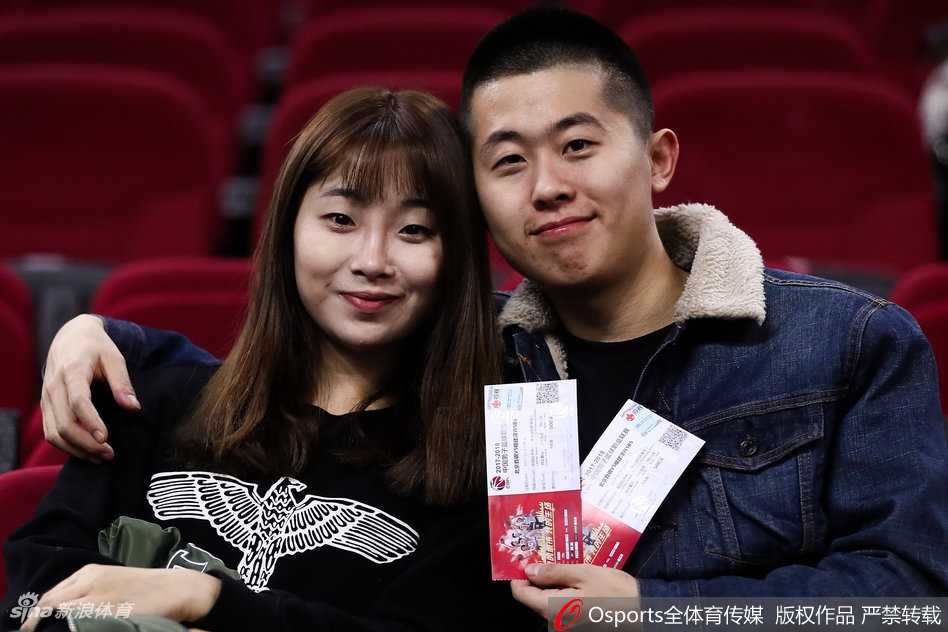 京城篮球之夜,美女球迷点亮看台风景线 一位长发披肩的美女球迷,眼神专注地盯着赛场方向,嘴角带着浅浅的笑意,手中挥舞着助威棒,仿佛下一秒就要为北京队的一次精彩进攻而欢呼。