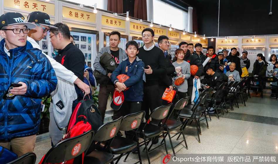 京城篮球传奇的温情瞬间:老马退役见面会,小球迷送上最纯真的吻 人山人海的签售大厅里,马布里坐在桌前专注地为球迷签名,背景墙上挂着他不同时期的经典照片,排队的球迷们井然有序地向前移动,手中拿着海报和纪念品,眼神中充满期待。