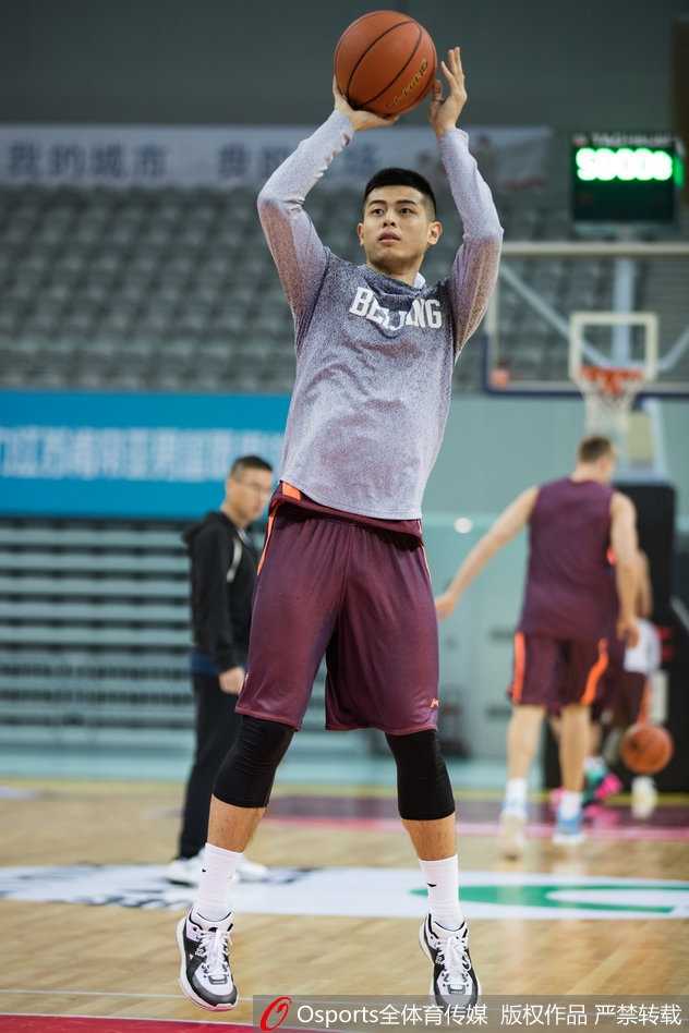 刘晓宇身着便装在场边独自进行拉伸，眼神中透露出渴望上场却又不得不耐心等待的复杂情绪