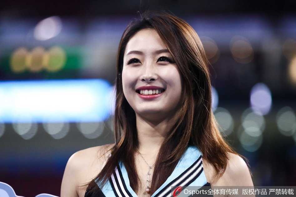 北京首钢篮球宝贝们身着一袭红白相间的动感队服，在马尾辫的飞扬中，她们的笑容比主场灯光还要耀眼，瞬间点燃了五棵松的冬日热情。