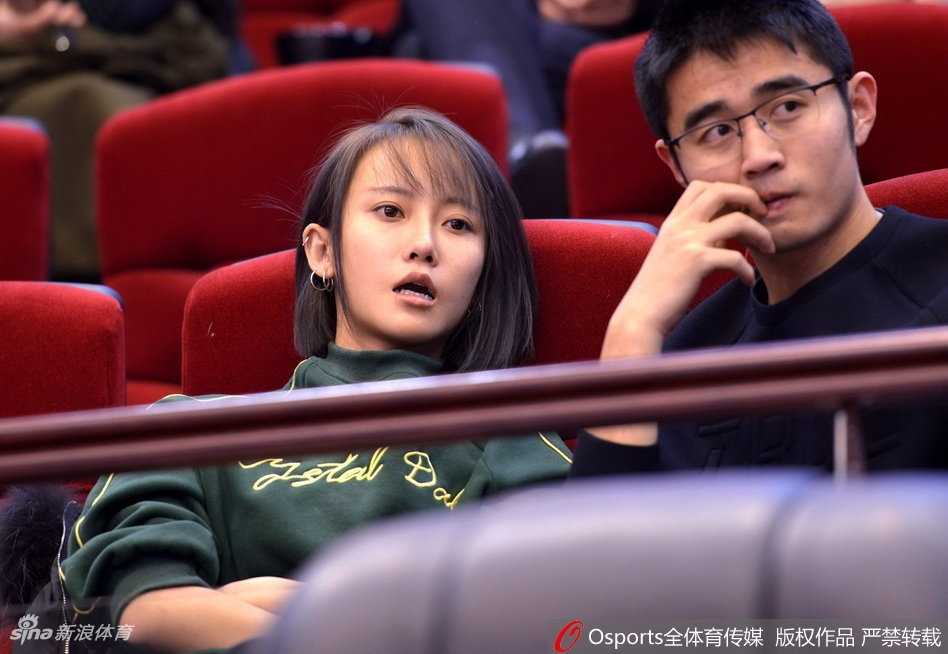 京鲁大战加时绝杀,丁彦雨航封神之夜 一位气质优雅的女球迷,手持加油棒,目光坚定地望向球场中央,在激烈的比赛氛围中显得格外从容和投入。