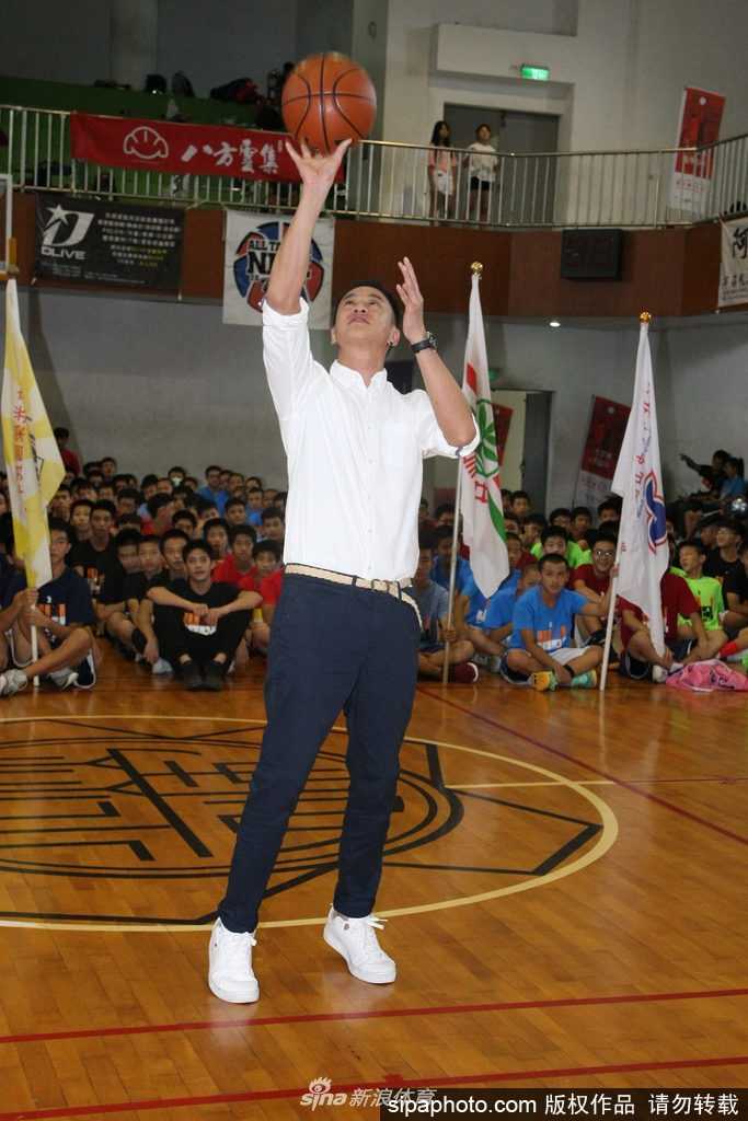 活动间隙何润东被热情的同学们团团围住，他亲切地低头与小球员交谈，画面充满了运动与友谊的温暖气息。