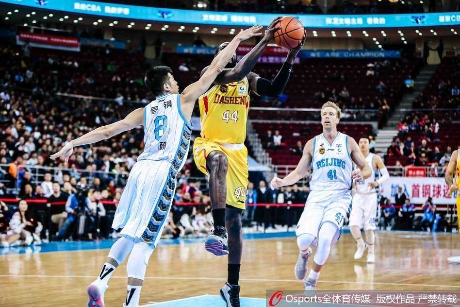 刘晓宇廿一分引领团队胜利 北京首钢主场击退南京同曦 赛后,北京首钢球员们围成一圈,互相击掌鼓励,脸上洋溢着胜利的喜悦,背景是五棵松体育馆内飘扬的旗帜。