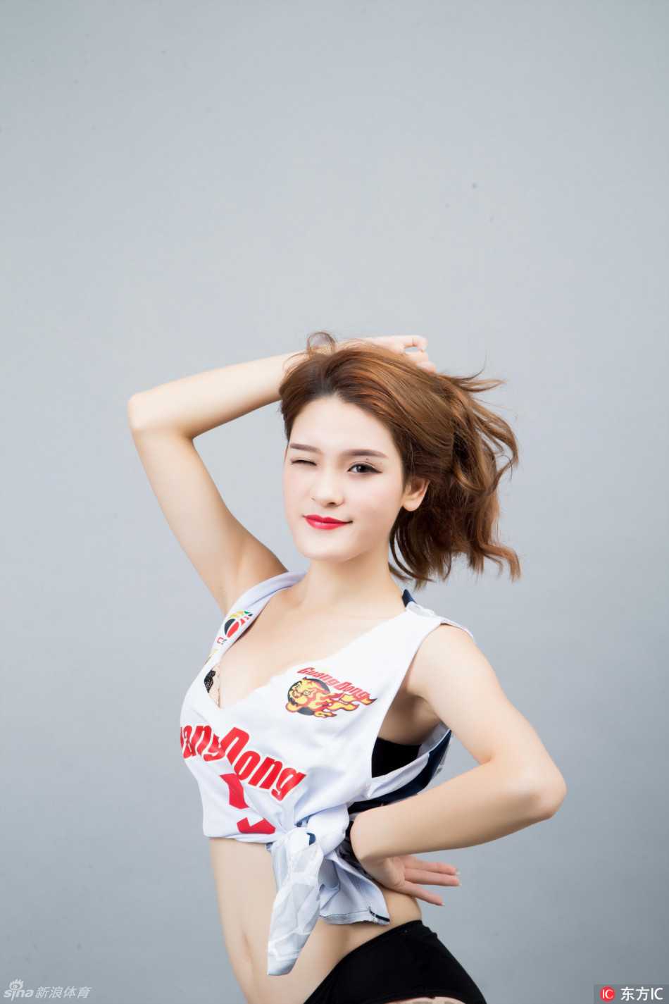 华南虎主场绽放巾帼红,篮球宝贝舞动东莞燃爆逆袭希望 一位篮球宝贝在表演间隙看向镜头,精致的五官和甜美的笑容与背后激烈的比赛形成鲜明对比,展现出体育世界中刚柔并济的独特魅力。