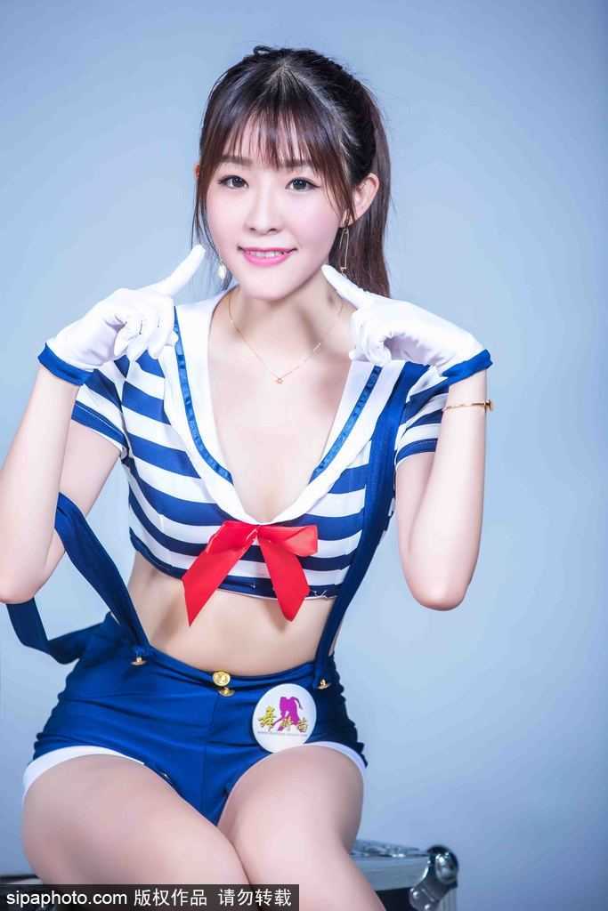 一位队员倚靠在球场边的栏杆上，水手服的裙摆微微飘动，她手持一个助威花球，神情专注地看向远方，仿佛在沉思如何能更好地为球队在客场征战时注入精神动力。